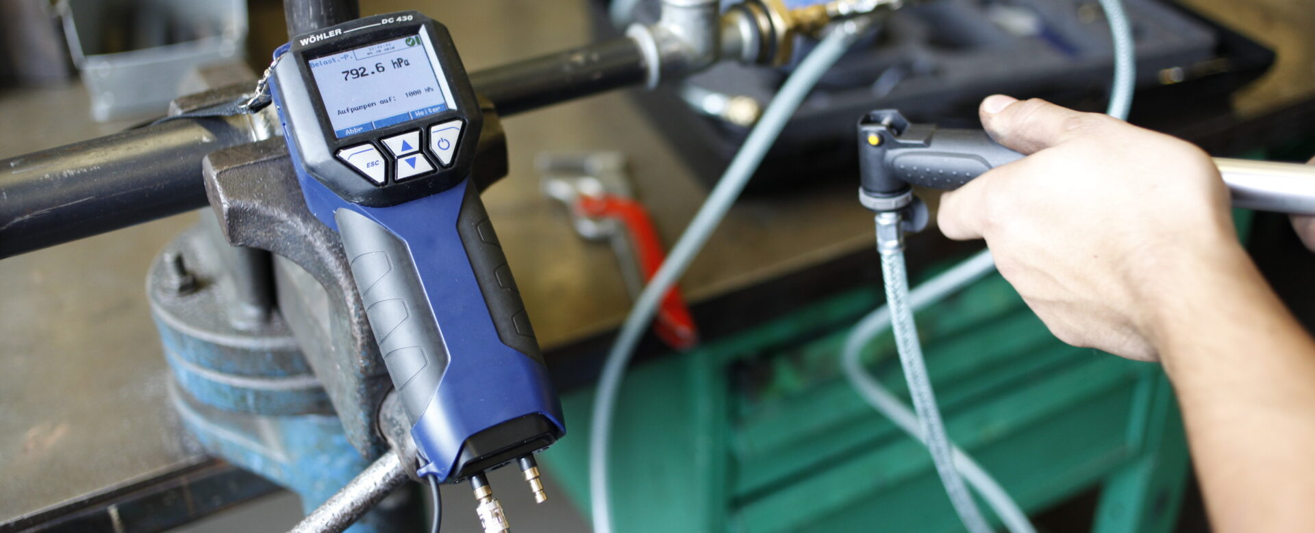 Mann überprüft Gasdruck mit einem Manometer an einer Metallleitung in einer Werkstattumgebung.