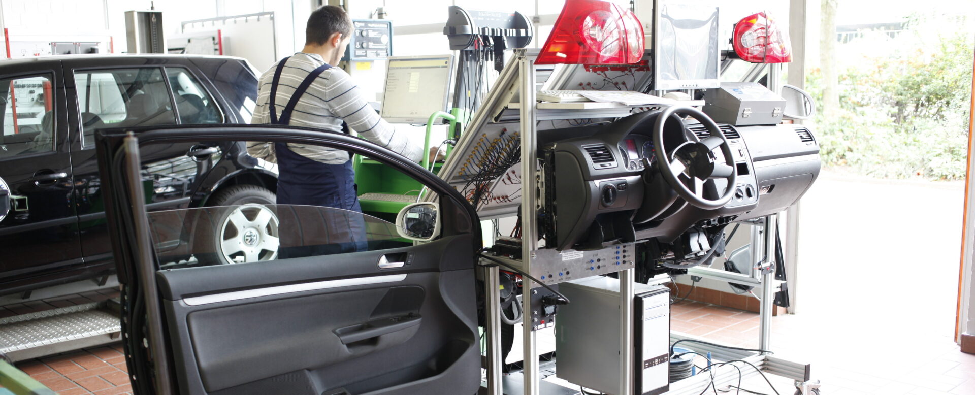 Techniker testet Armaturenbrett und Elektrik eines Autos in einer Werkstatt mit computergesteuerter Diagnosestation.